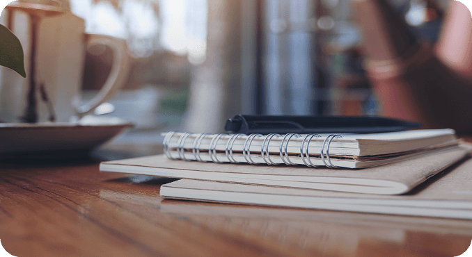 Notebooks and a pen on a wooden desk