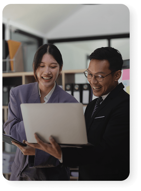 Two business professionals smiling and looking at a laptop.